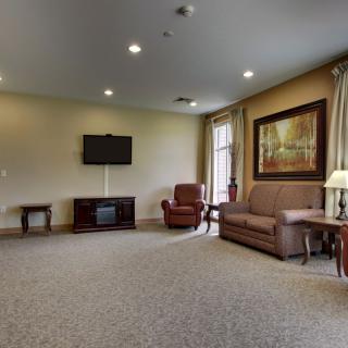 A spacious living room with a sofa, armchair, TV, and decorative elements.