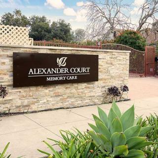 Entrance sign for Alexander Court Memory Care with surrounding plants.