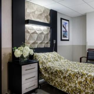 A modern hospital room with a neatly made bed and stylish decor.