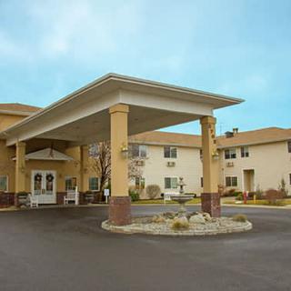 Exterior view of a hotel entrance with a covered driveway and parking area.