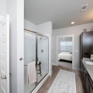A modern bathroom featuring a glass-door shower, sink with mirror, and neutral decor.