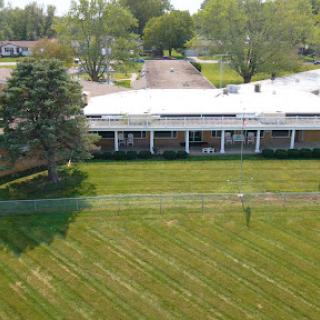 Aerial view of a building surrounded by a well-maintained grassy area and trees.