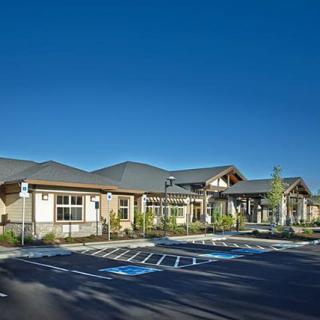 A modern building with a parking lot and clear blue sky in the background.