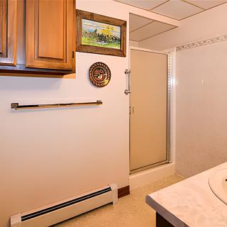 A bathroom with a wooden cabinet, shower, and wall decorations.