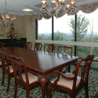 A well-furnished conference room with a large wooden table and elegant chandeliers.