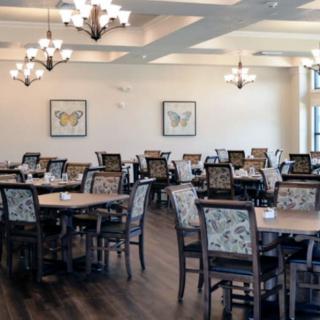 An elegant and spacious dining area with neatly arranged tables and chairs, illuminated by stylish chandeliers.