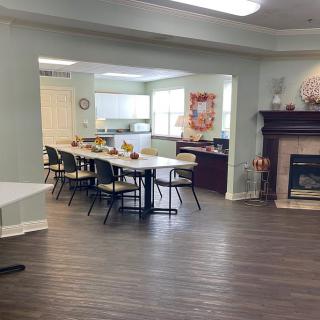 A cozy dining area with tables and chairs set up near a kitchen and fireplace.