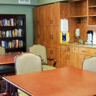 A meeting room with tables, chairs, a bookshelf, and a coffee station setup.