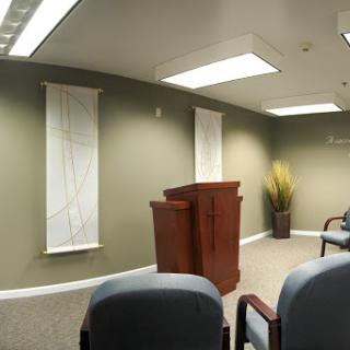 A well-lit office meeting room featuring a wooden podium, comfortable seating, and minimalist decor.