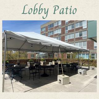 An outdoor lobby patio with a tent and seating area.