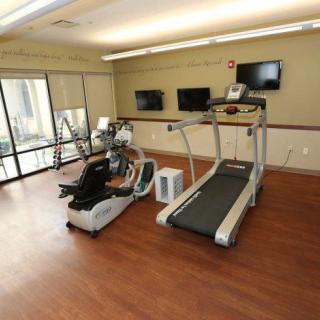 A fitness center featuring a treadmill and stationary bike with TV screens on the wall.