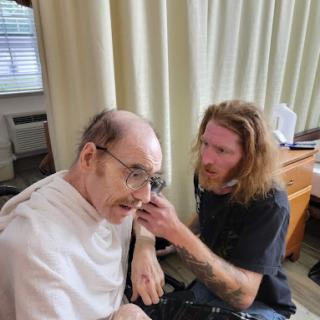 A caregiver attentively assists an elderly individual indoors.