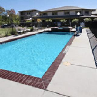 An outdoor swimming pool adjacent to a building on a sunny day.