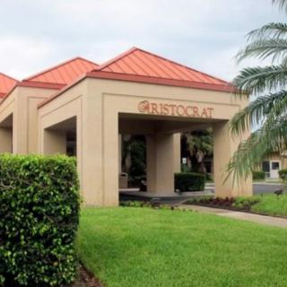 A view of a building entrance with a landscaped lawn and palm tree.