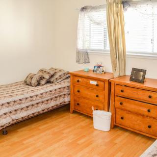 A cozy bedroom with a single bed and matching wooden furniture, including a dresser and nightstand.