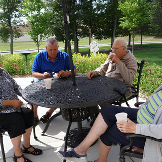 A group of seniors sitting and relaxing at a table outdoors.