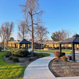 A serene park featuring winding pathways, gazebos, and lush greenery under a clear blue sky.