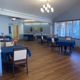 A spacious restaurant interior featuring blue tablecloths and wooden flooring, creating a welcoming atmosphere.