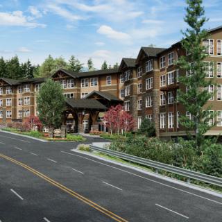 A multi-story residential building with a road in front, surrounded by trees and greenery.