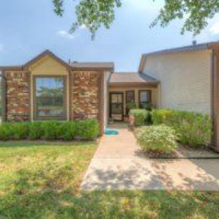 A single-story brick house with a landscaped front yard and a welcoming pathway.