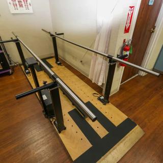 An indoor setup of parallel bars used for physical therapy and rehabilitation exercises.