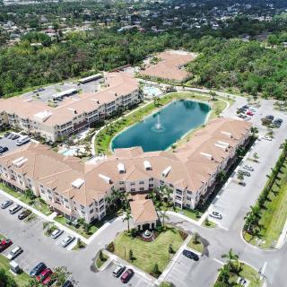 Aerial view of a building complex with a central lake and surrounding greenery.