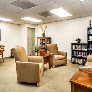 An office waiting area with comfortable chairs and a bookshelf.