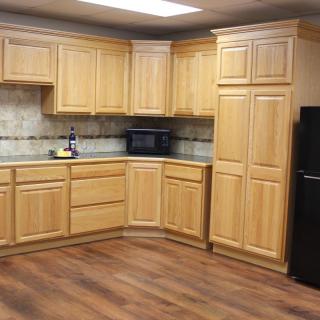 A modern kitchen with wooden cabinets and a black refrigerator.