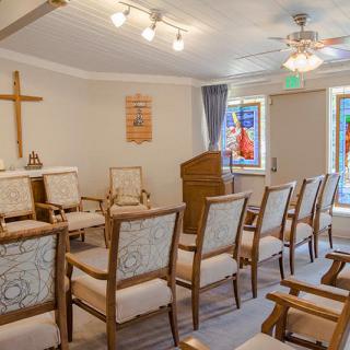 A small chapel with arranged seating, a pulpit, and stained glass windows.