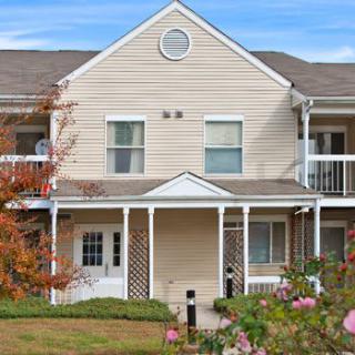 A two-story suburban duplex with a covered porch and a landscaped front yard.
