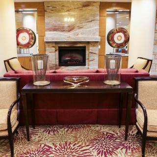 A cozy living room with a central fireplace, surrounded by comfortable chairs and elegant decor.
