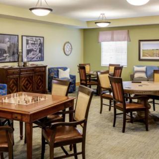 A well-lit room featuring multiple tables and chairs, decorated with wall art and cozy furnishings.