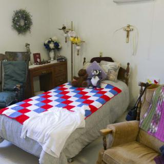 A cozy bedroom with a colorful quilt on the bed and decorative items around.