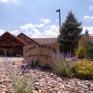 A view of a building with a sign reading 'Pine Hills' surrounded by landscaping and under a clear sky.