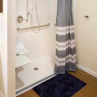 Accessible shower with a grab bar and striped curtain.