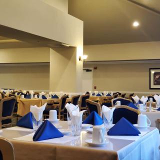 A well-arranged restaurant dining area with neatly set tables featuring blue napkins and white tablecloths.