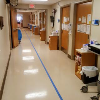 A clean hospital hallway with blue tape marking the floor.