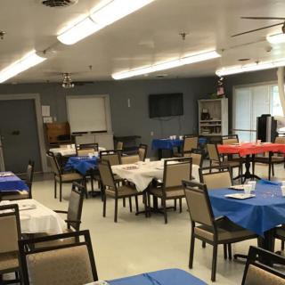A neatly arranged dining area with several tables and chairs, each table covered with colorful tablecloths.