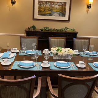 A neatly set dining table with blue placemats and white floral centerpiece.