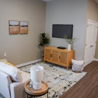 A modern and minimalist living room with a cozy seating area, wall-mounted TV, and stylish decor.