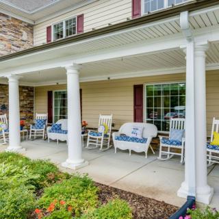 A cozy porch with rocking chairs and columns, overlooking a landscaped garden.