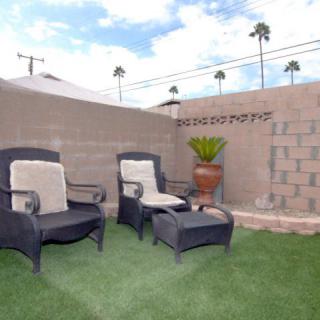 A cozy outdoor patio with comfortable seating and a potted plant against a brick wall.