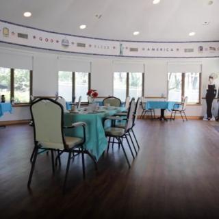 A bright event hall set up with tables and chairs, decorated with blue tablecloths.
