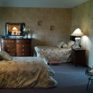 A cozy bedroom with two beds, a dresser, and a lamp.