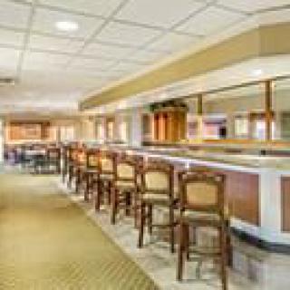 An empty bar interior with a row of wooden chairs lined up along the counter.