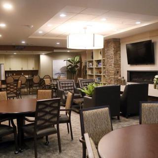 A modern lounge area with tables, chairs, and a television.