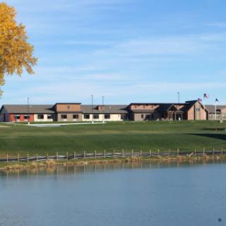 A serene view of a building by the lake under a clear blue sky.