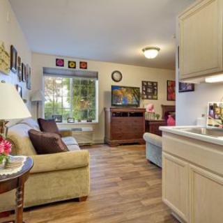 A cozy living room with a sofa, TV, and wooden flooring.