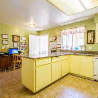 A bright kitchen with yellow cabinets and a central island, featuring a homey decor and ample natural light.