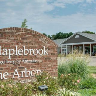A brick sign in front of a retirement community building on a clear day.